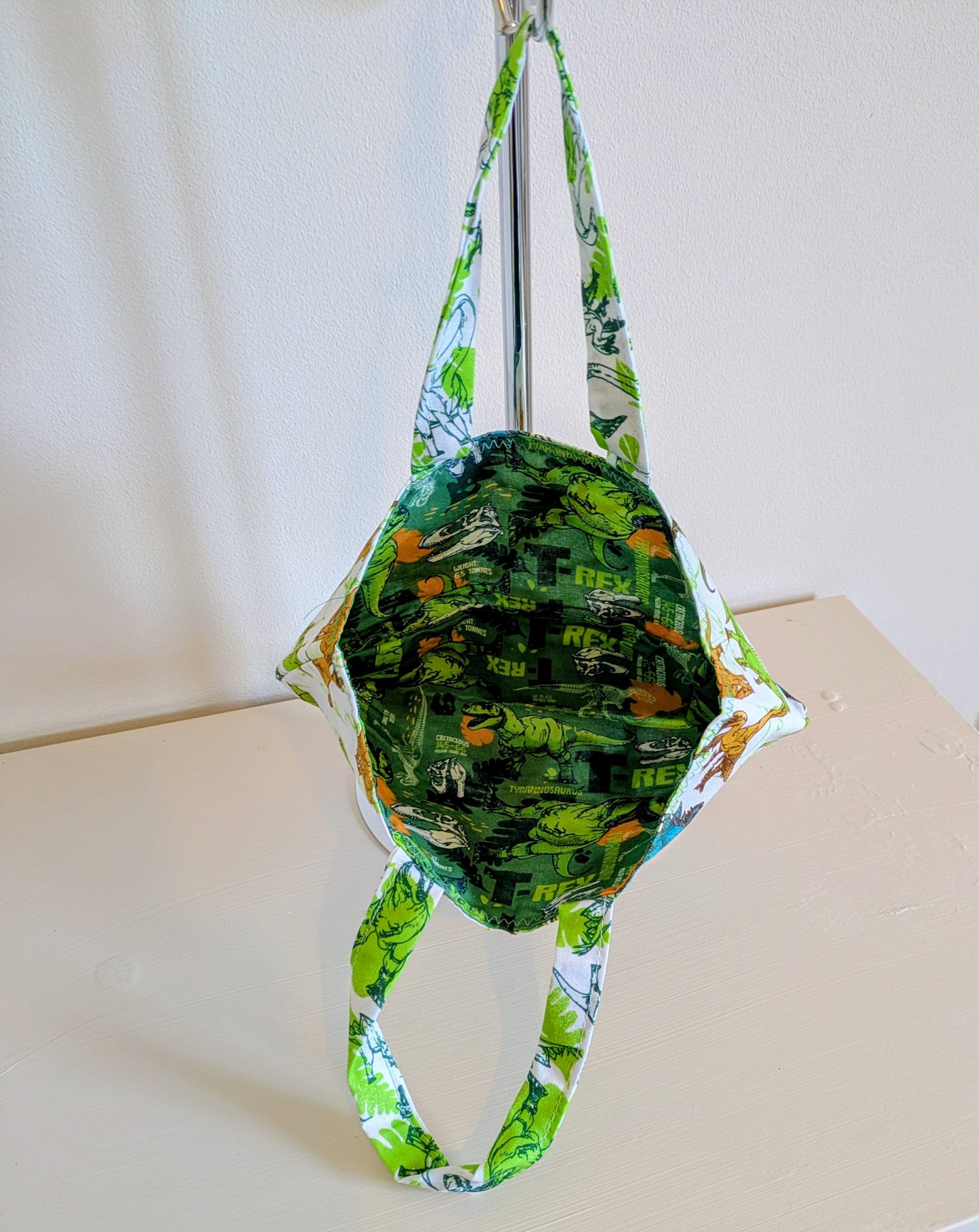 Harrie's Crafts dinosaur tote bag featuring a colorful dinosaur print on durable fabric with sturdy handles.