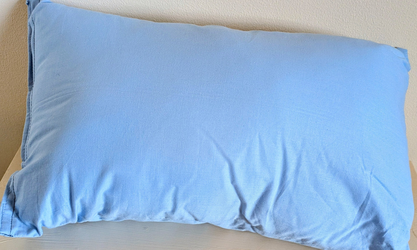 Harrie's Crafts heart cushion with soft fabric and decorative stitching, placed on a cozy wooden surface.
