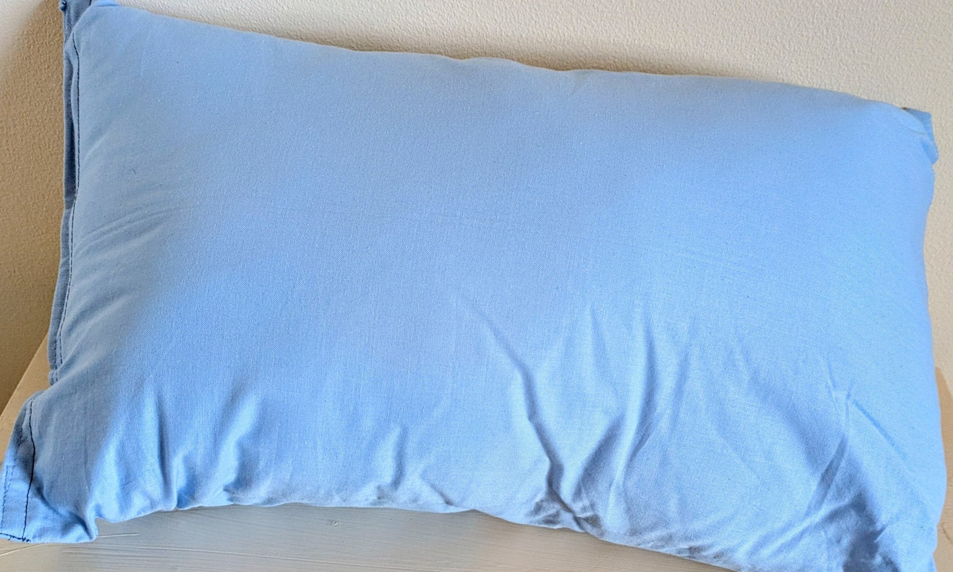 Harrie's Crafts heart cushion with soft fabric and decorative stitching, placed on a cozy wooden surface.