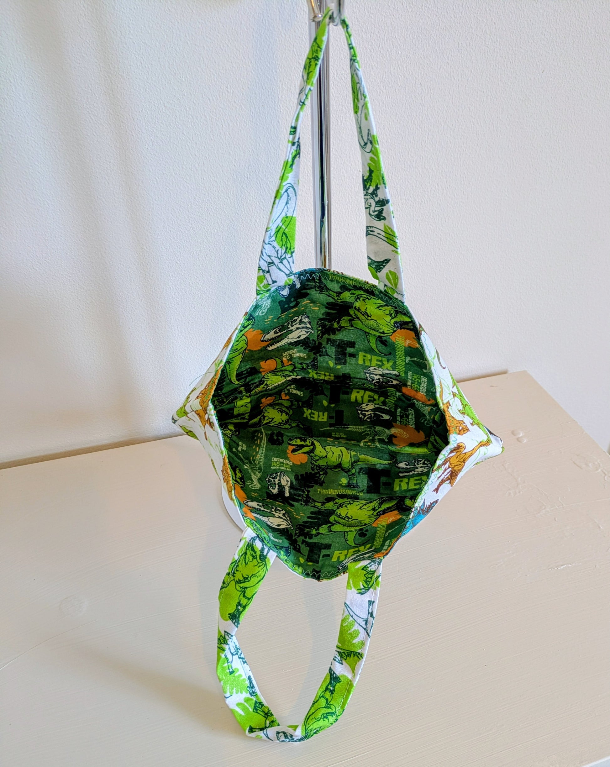Harrie's Crafts dinosaur tote bag featuring a colorful dinosaur print on durable fabric with sturdy handles.