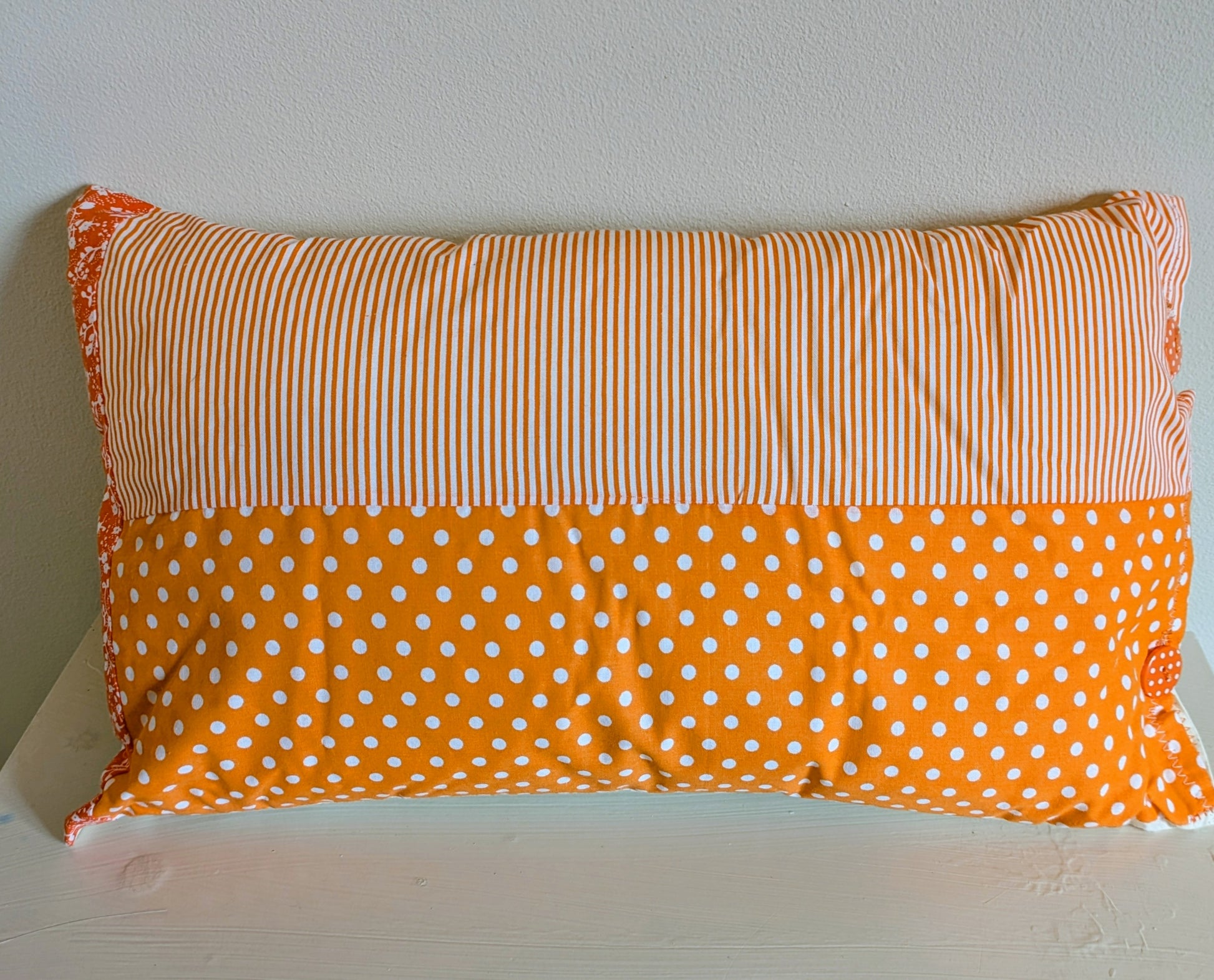 Orange patchwork cushion by Harrie's Crafts featuring vibrant mixed fabric squares and a soft, plush texture.