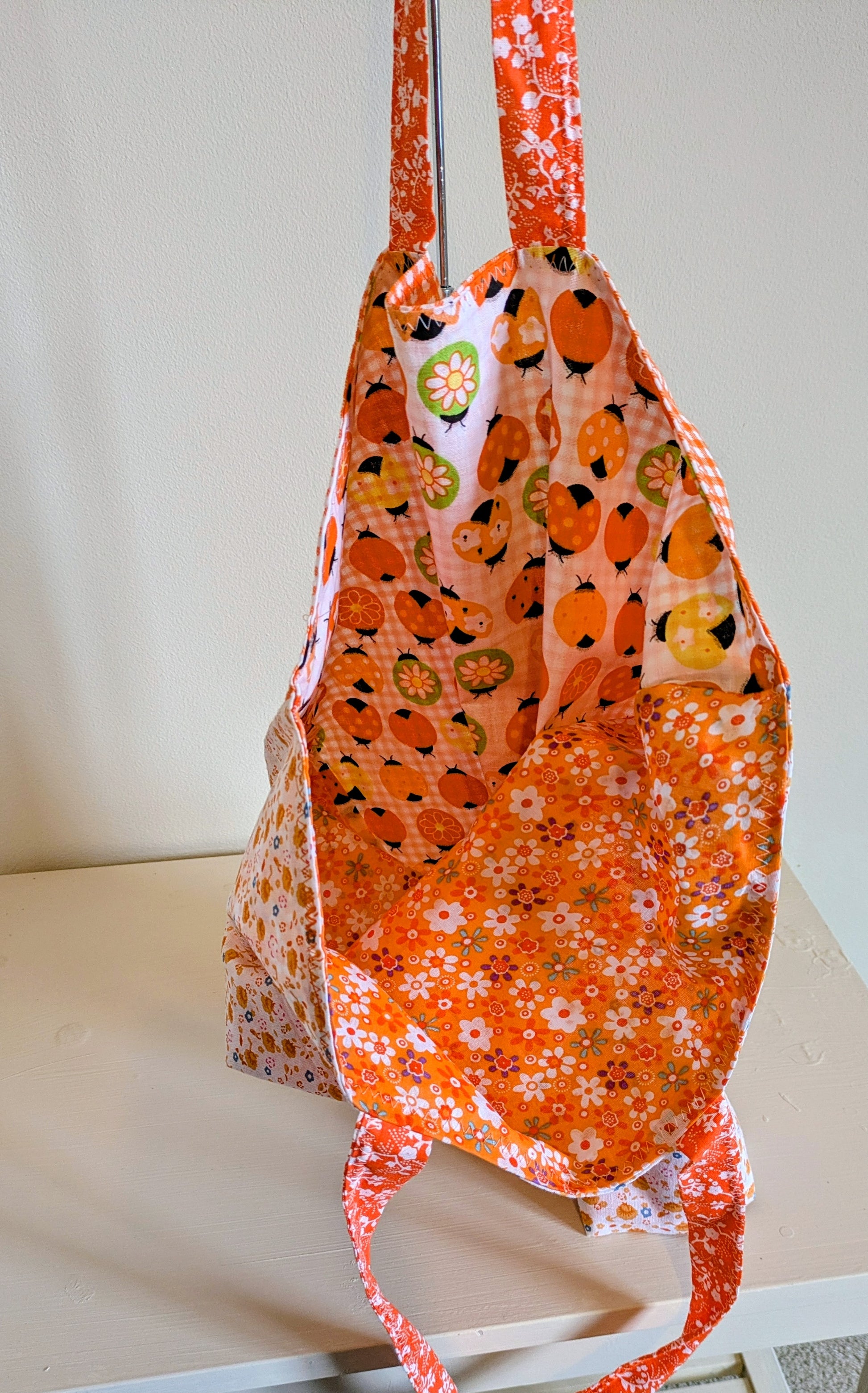Orange tote bag by Harrie's Crafts with sturdy handles and spacious interior, shown on a plain background.