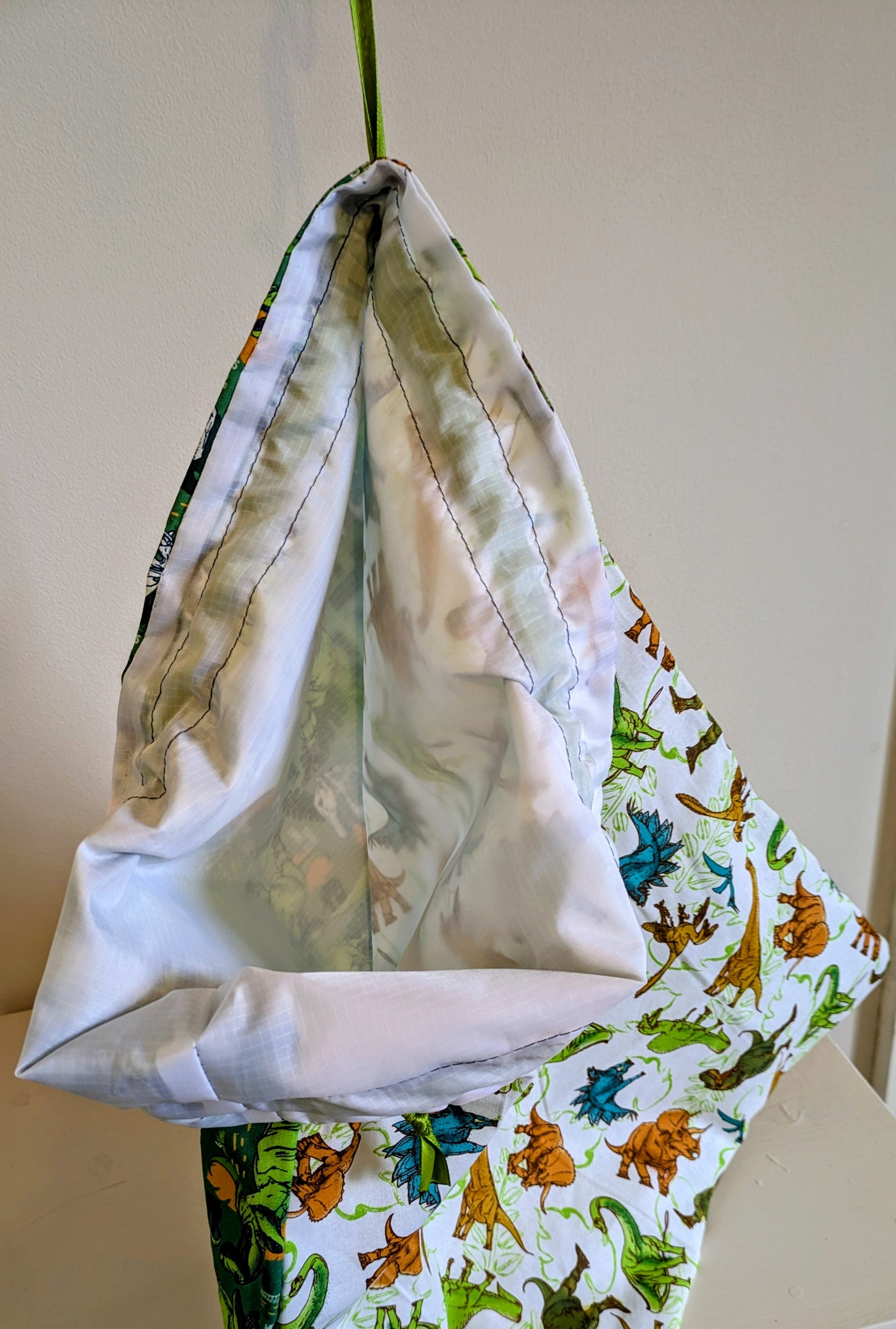 Colorful dinosaur waterproof drawstring bag by Harrie's Crafts with vibrant dinosaur illustrations and durable waterproof fabric.