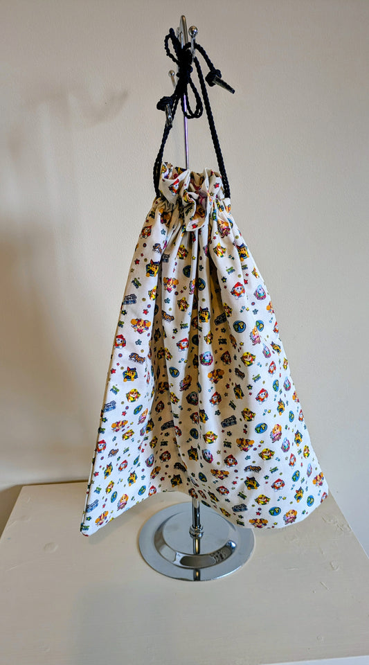 Harrie's Crafts Paw Patrol drawstring bag featuring colorful cartoon pups and a secure cinch closure.
