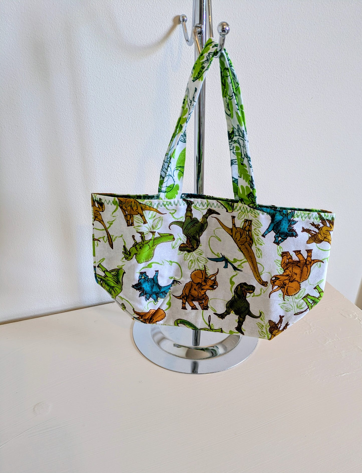 Harrie's Crafts dinosaur tote bag featuring colorful dinosaur illustrations on natural fabric, perfect for casual use and daily errands.