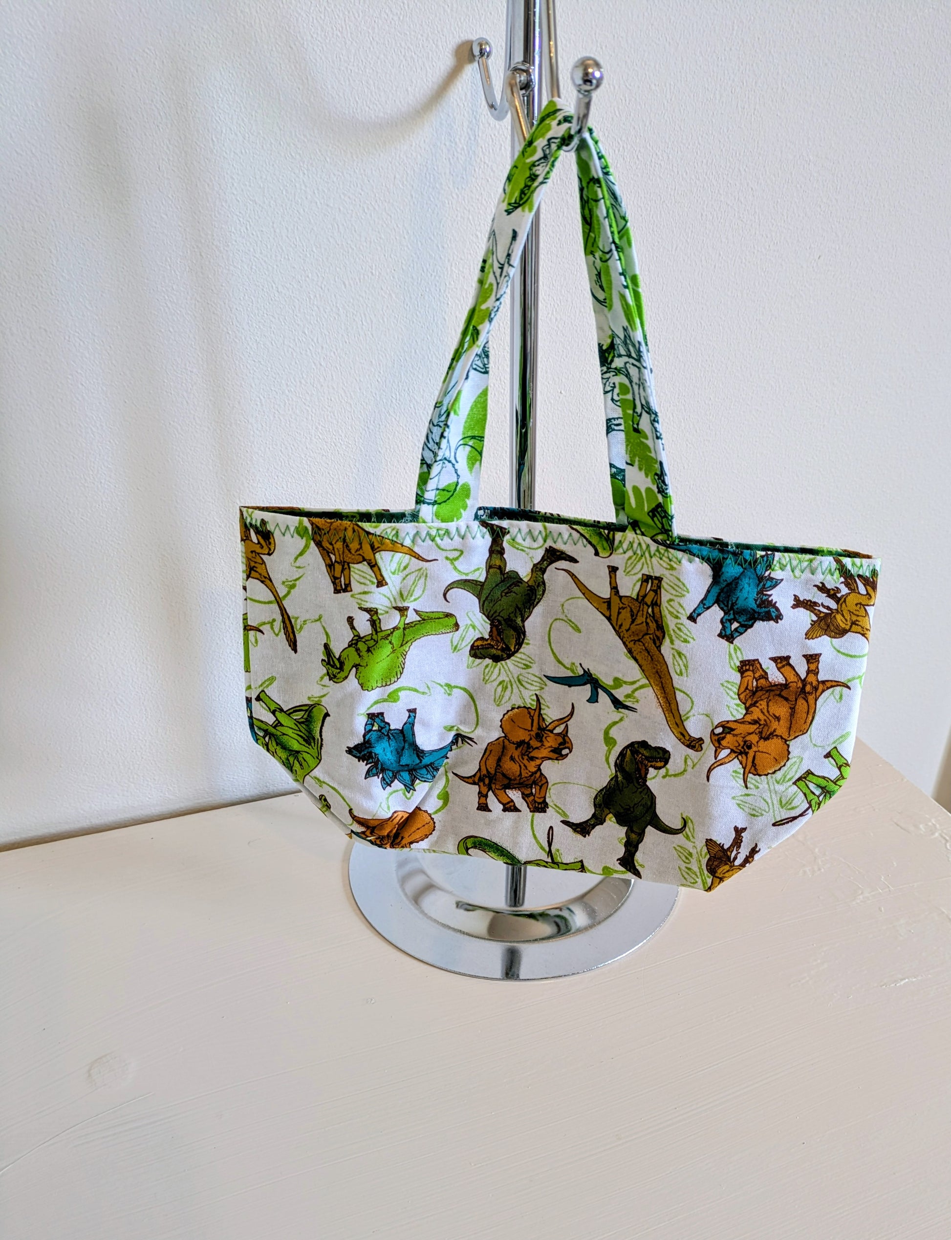 Harrie's Crafts dinosaur tote bag featuring colorful dinosaur illustrations on natural fabric, perfect for casual use and daily errands.